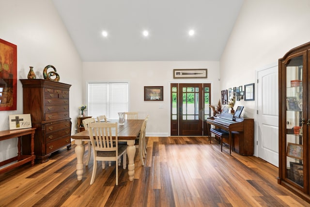 dining space featuring high vaulted ceiling and dark wood-type flooring