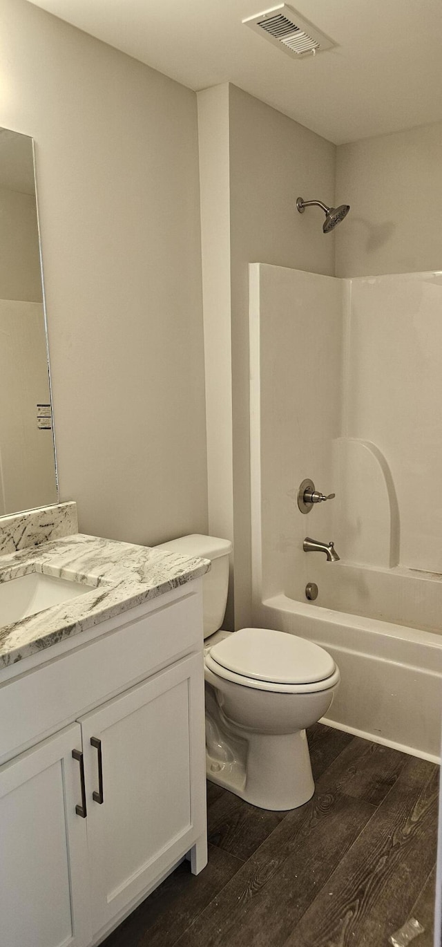 bathroom featuring toilet, wood finished floors, vanity, bathing tub / shower combination, and visible vents