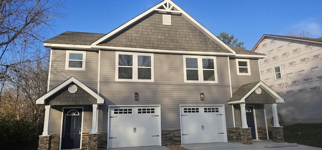 craftsman house with a garage, concrete driveway, and stone siding