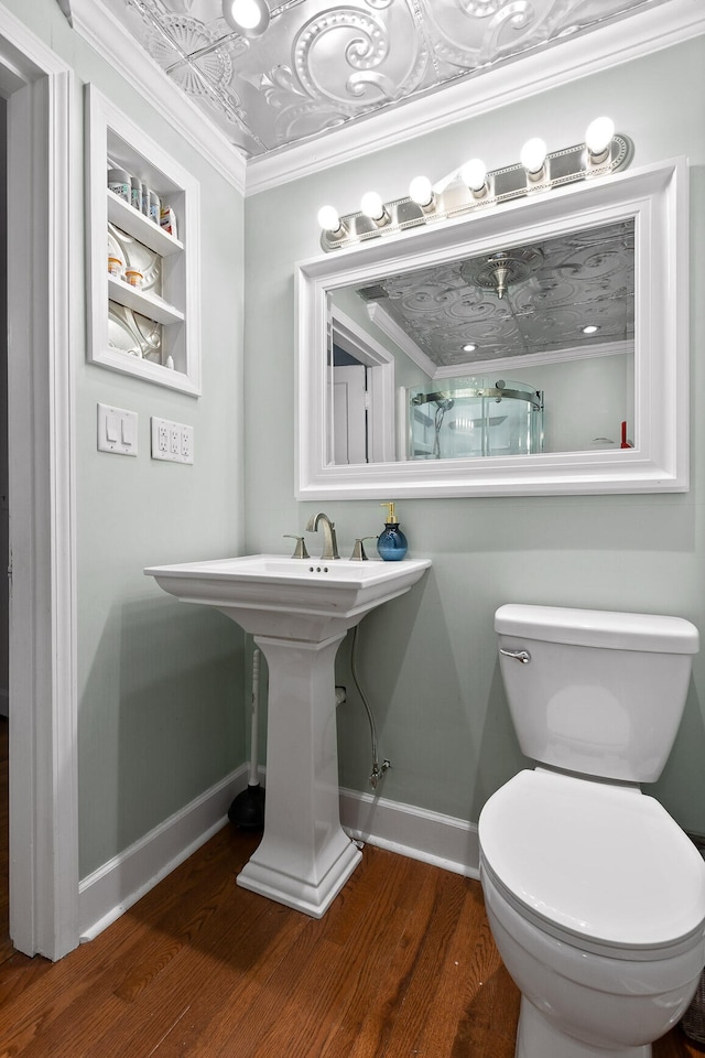 bathroom with wood-type flooring, crown molding, and toilet