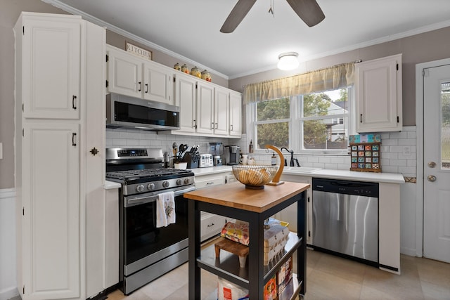 kitchen with appliances with stainless steel finishes, crown molding, tasteful backsplash, and white cabinets