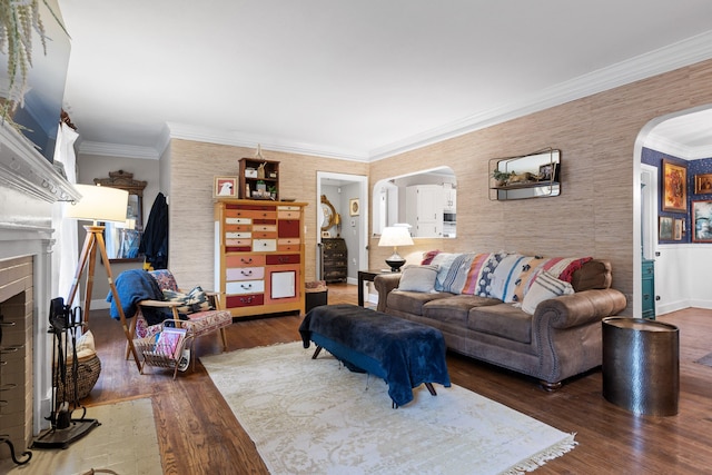 living room with ornamental molding, a brick fireplace, and dark wood-type flooring