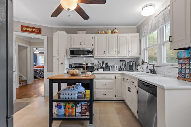 kitchen with appliances with stainless steel finishes, white cabinetry, sink, and ceiling fan