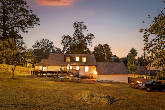 back house at dusk featuring a deck and a yard