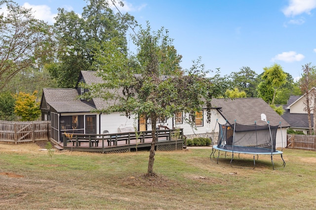 back of house with a trampoline, a deck, a yard, and a sunroom