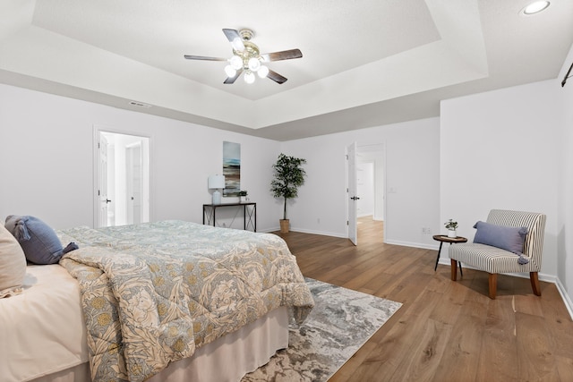 bedroom featuring ceiling fan, a raised ceiling, and hardwood / wood-style floors