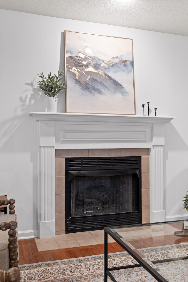 details featuring wood-type flooring, a textured ceiling, and a tile fireplace