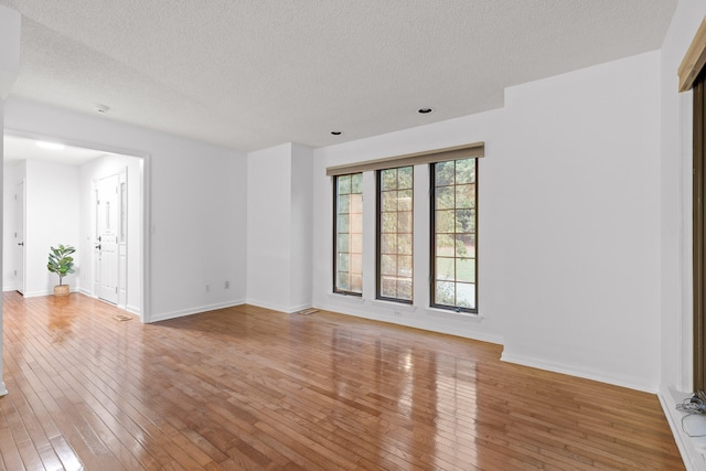 spare room with a textured ceiling and wood-type flooring