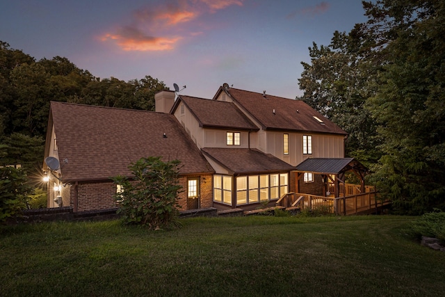 back house at dusk featuring a deck and a yard