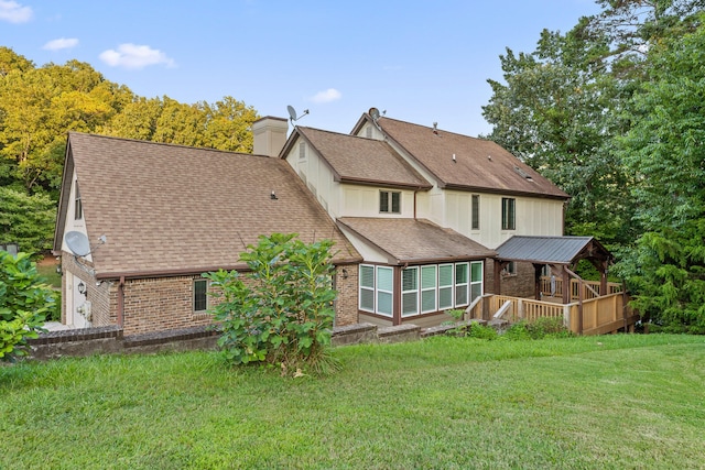 back of property featuring a wooden deck, a garage, and a lawn