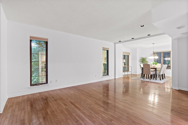 interior space featuring an inviting chandelier, a textured ceiling, and hardwood / wood-style floors