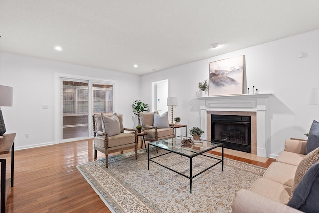 living room featuring a tile fireplace and light hardwood / wood-style floors