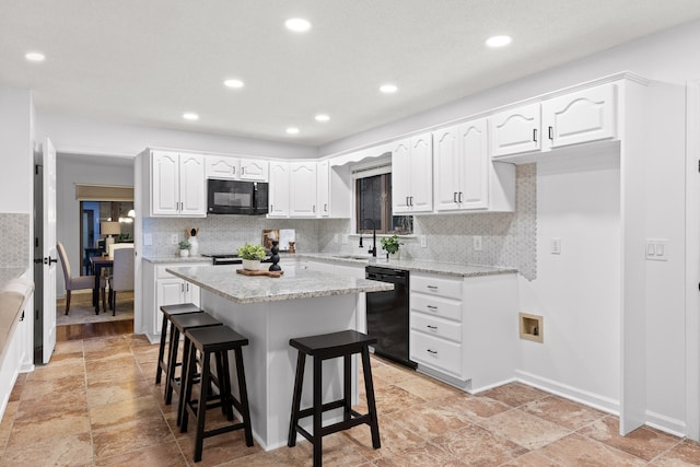 kitchen featuring a kitchen breakfast bar, white cabinets, a kitchen island, black appliances, and sink