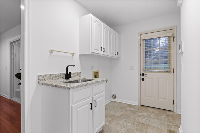 clothes washing area featuring washer hookup, cabinets, light wood-type flooring, and sink