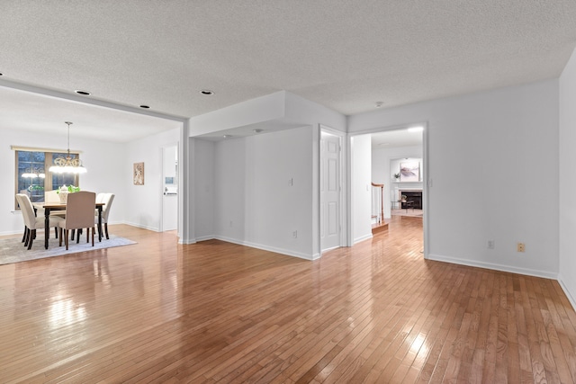 unfurnished living room with a textured ceiling, light hardwood / wood-style flooring, and a chandelier