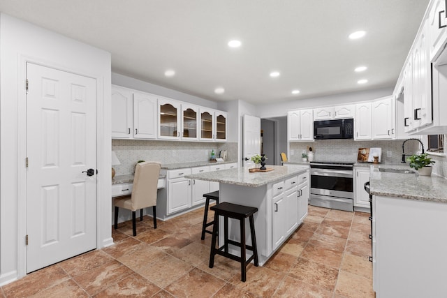 kitchen featuring white cabinets, a kitchen island, tasteful backsplash, and stainless steel electric range