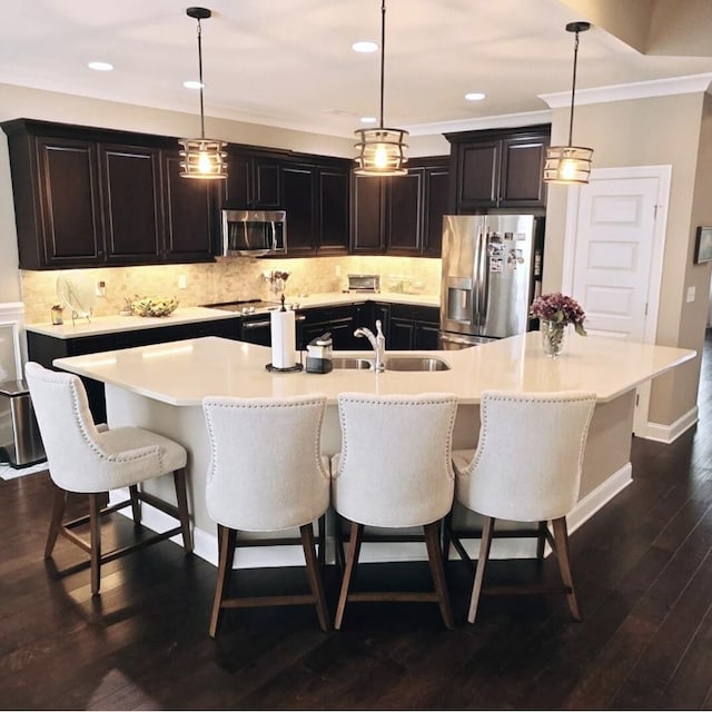 kitchen with a large island with sink, dark hardwood / wood-style flooring, pendant lighting, and stainless steel appliances