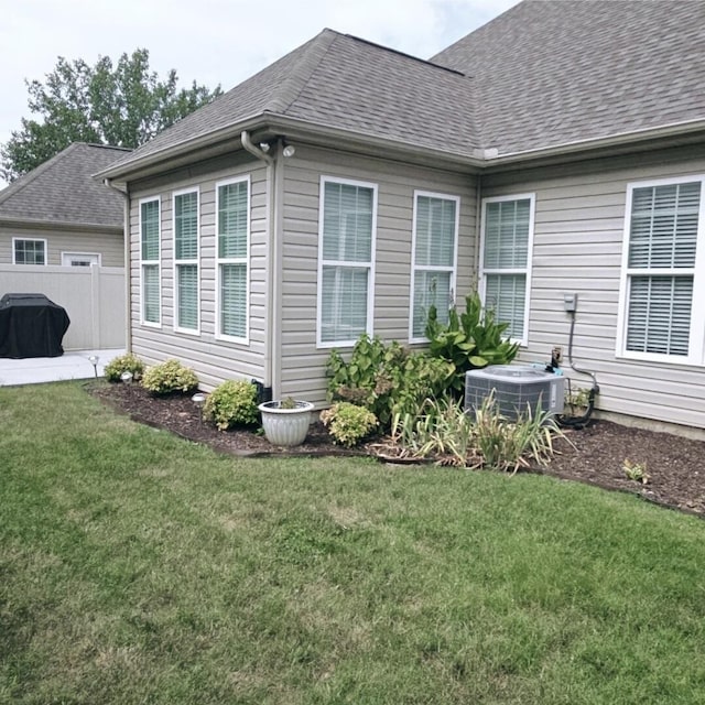 view of side of property with central AC unit and a yard