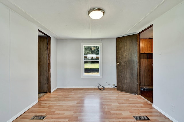 spare room featuring wooden walls and light hardwood / wood-style flooring