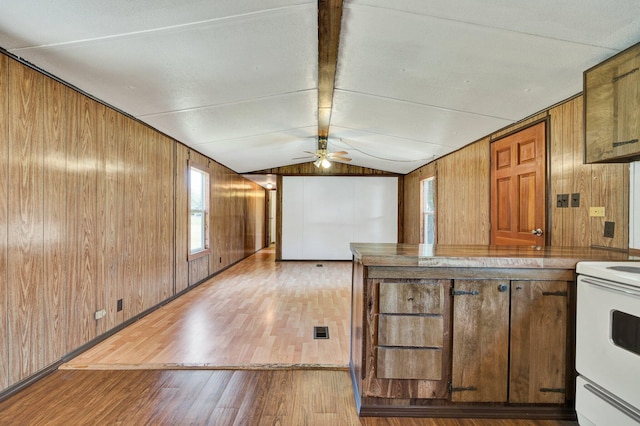 kitchen featuring light wood-type flooring, lofted ceiling, ceiling fan, and wood walls