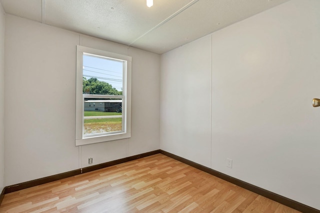 empty room featuring a textured ceiling and light hardwood / wood-style floors