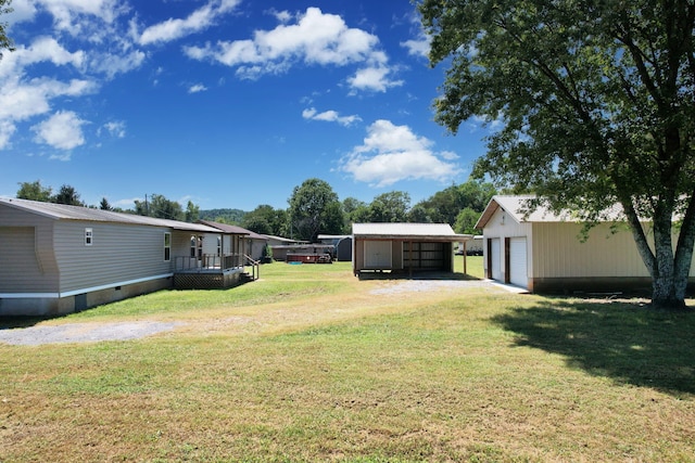 view of yard featuring a garage, a wooden deck, and an outbuilding