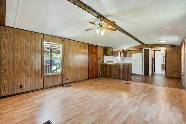 unfurnished living room featuring ceiling fan, wooden walls, and light hardwood / wood-style floors