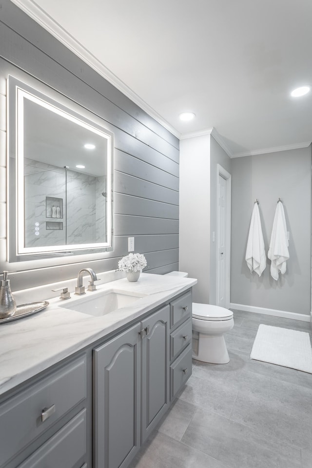 bathroom with a tile shower, vanity, crown molding, and toilet