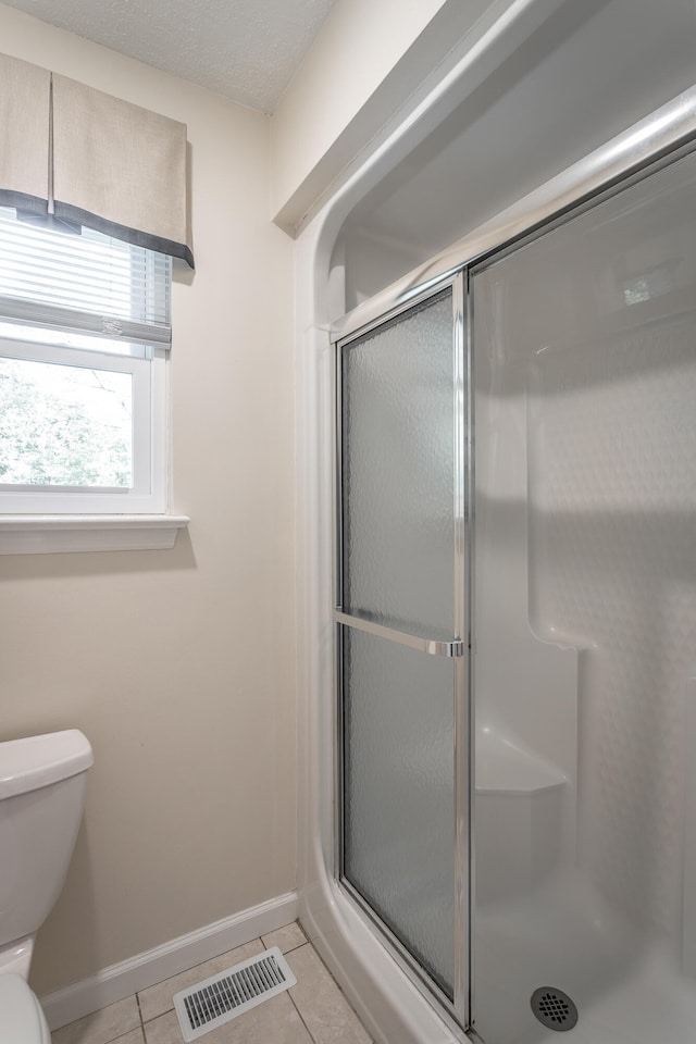 bathroom with walk in shower, tile patterned flooring, and toilet