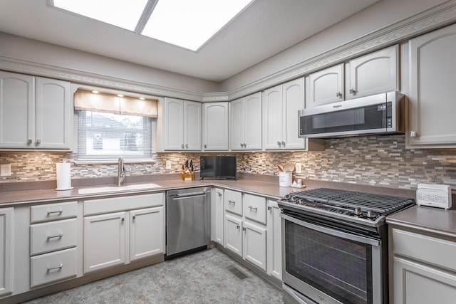 kitchen with decorative backsplash, white cabinets, appliances with stainless steel finishes, and sink