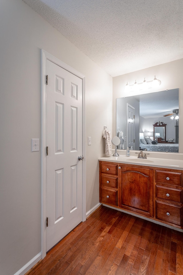 bathroom with ceiling fan, vanity, hardwood / wood-style floors, and a textured ceiling