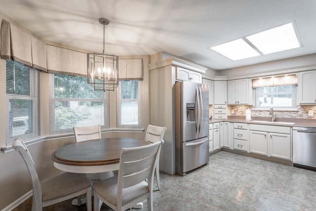 kitchen with white cabinetry, appliances with stainless steel finishes, decorative light fixtures, and sink