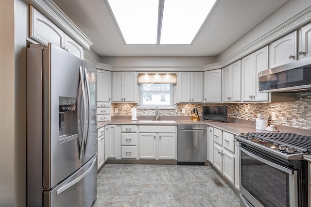 kitchen with white cabinets, stainless steel appliances, sink, and decorative backsplash