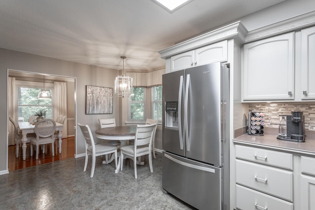 kitchen with white cabinets, stainless steel refrigerator with ice dispenser, a chandelier, and hanging light fixtures