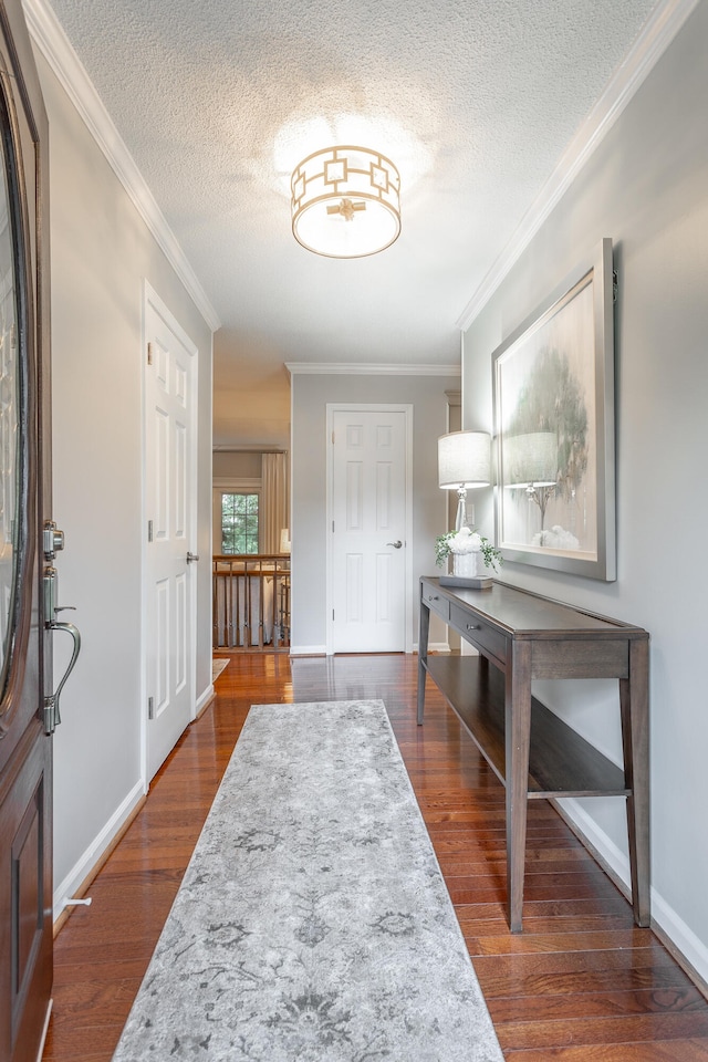 foyer with a textured ceiling, dark wood-type flooring, and crown molding