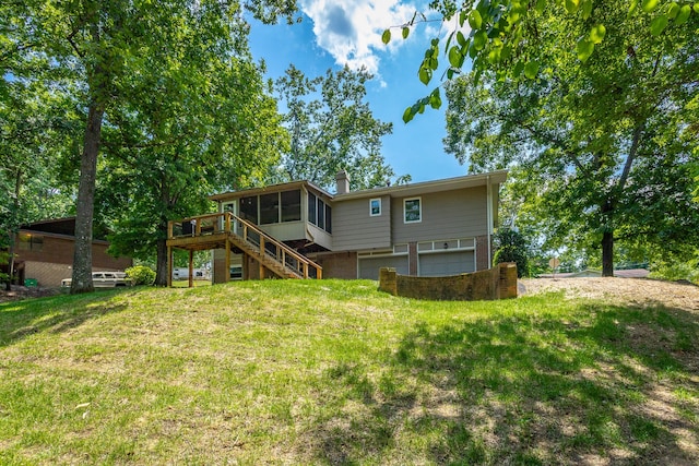 back of property featuring a deck, a yard, a garage, and a sunroom