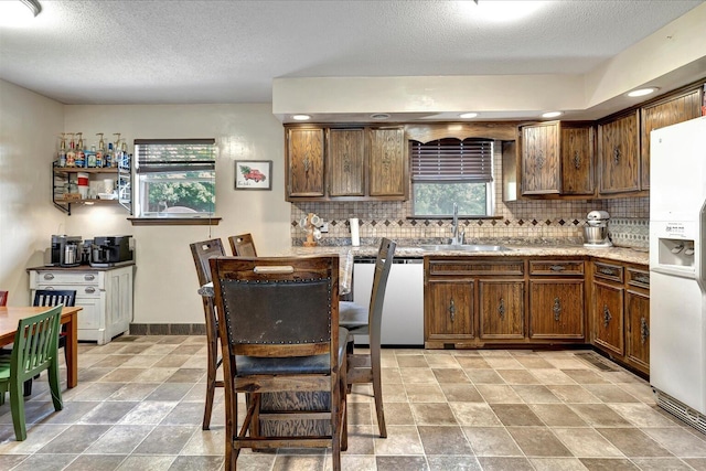 kitchen featuring tasteful backsplash, dishwasher, sink, and white refrigerator with ice dispenser