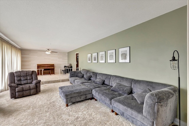 living room featuring ceiling fan, a fireplace, carpet floors, and a textured ceiling