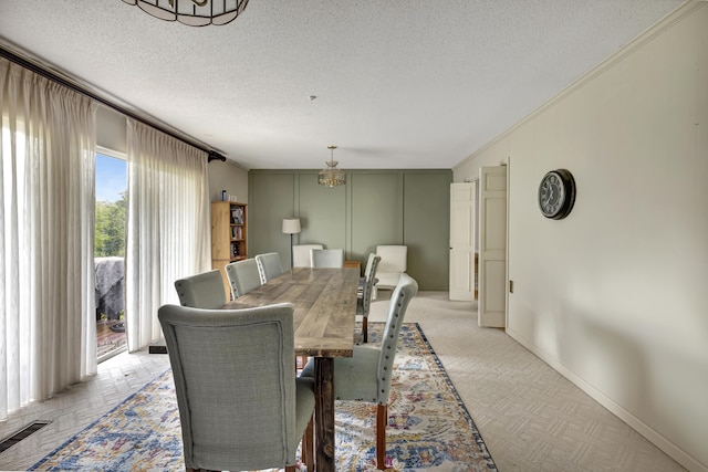 dining area featuring an inviting chandelier, light colored carpet, a textured ceiling, and ornamental molding