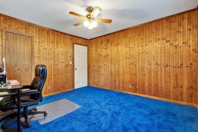 carpeted home office with ceiling fan, crown molding, and wood walls