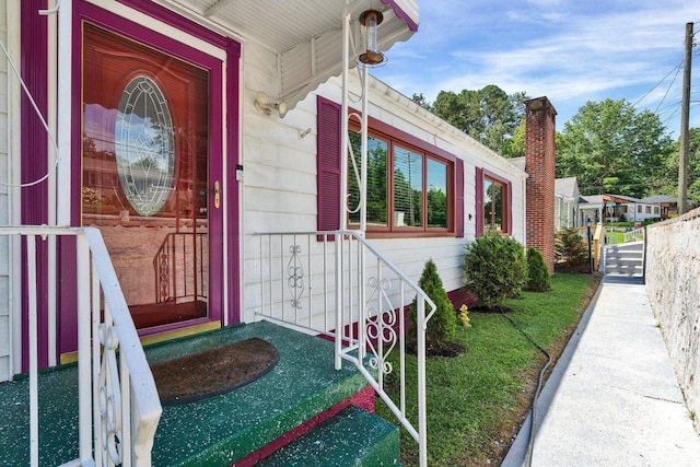 view of exterior entry with a porch and a yard