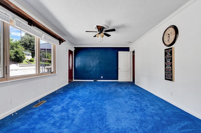 empty room with a textured ceiling, ornamental molding, dark colored carpet, and ceiling fan