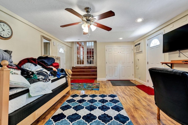 bedroom with a textured ceiling, ceiling fan, multiple windows, and hardwood / wood-style flooring