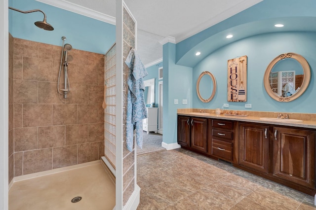 bathroom featuring a tile shower, vanity, ornamental molding, and tile patterned floors