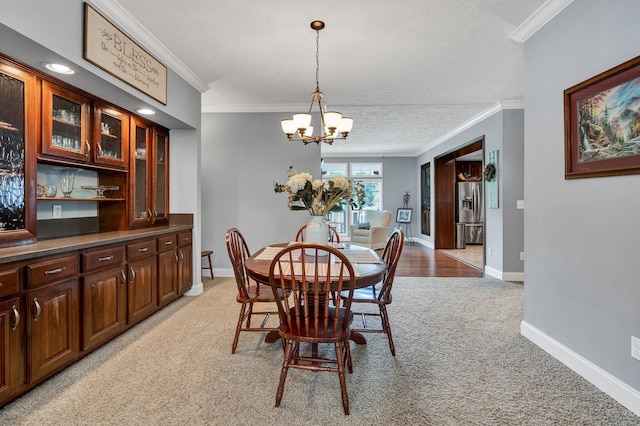 dining room with a notable chandelier, ornamental molding, a textured ceiling, and light carpet