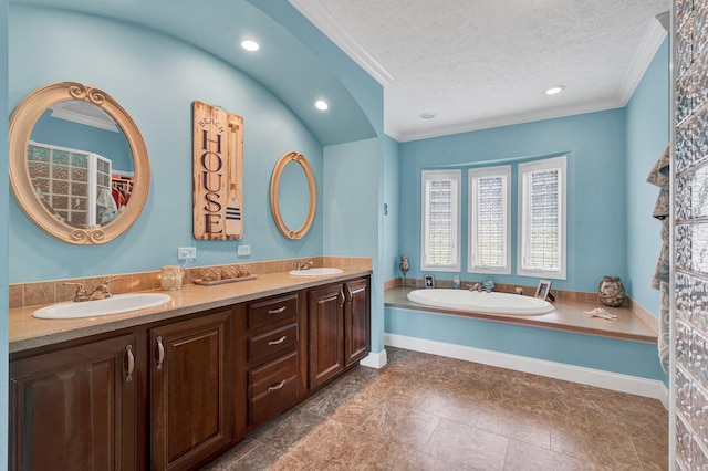 bathroom with ornamental molding, a tub to relax in, a textured ceiling, and vanity