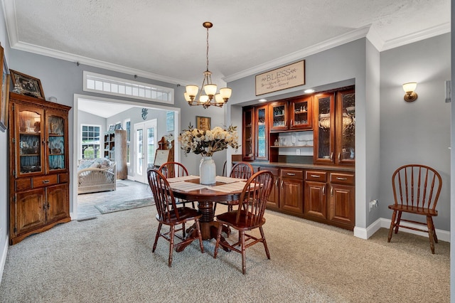 carpeted dining area with a textured ceiling, a chandelier, and ornamental molding