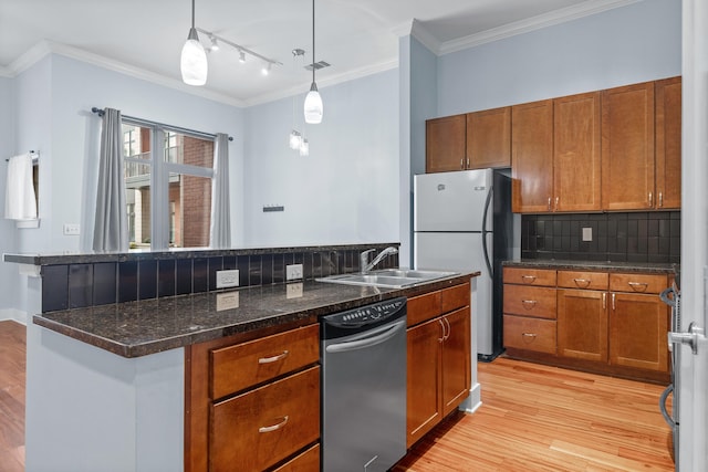 kitchen featuring tasteful backsplash, stainless steel refrigerator, light wood-type flooring, decorative light fixtures, and sink