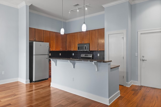 kitchen with hardwood / wood-style floors, decorative backsplash, a breakfast bar area, and stainless steel appliances