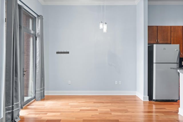 kitchen with light hardwood / wood-style flooring, pendant lighting, crown molding, and stainless steel refrigerator